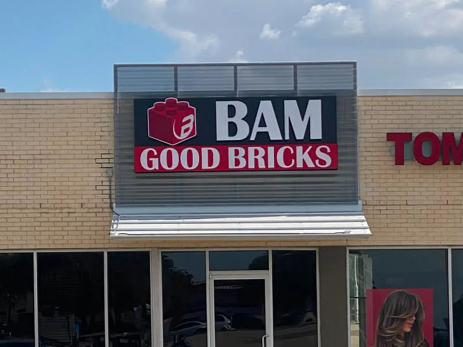 BAM Good Bricks sign with a red brick logo on a dark panel above a retail storefront