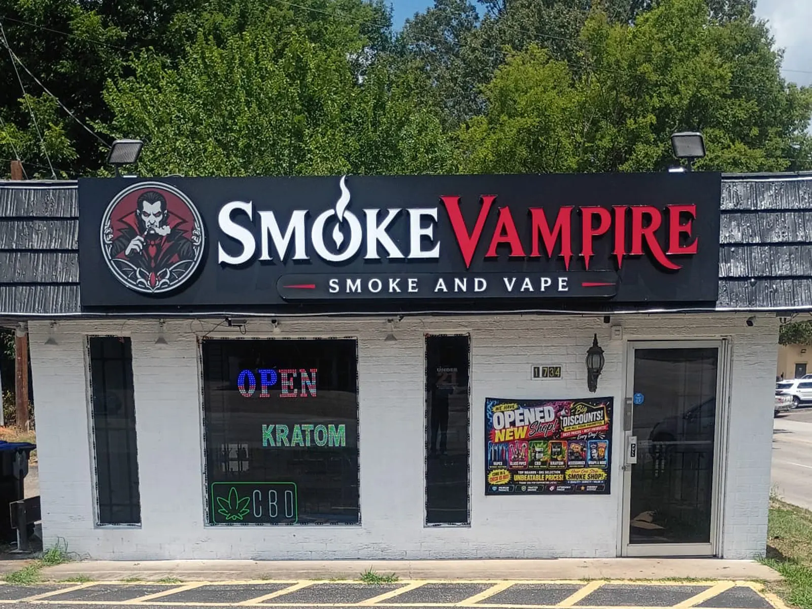 Smoke Vampire cabinet sign with a vampire logo above a small white brick shop